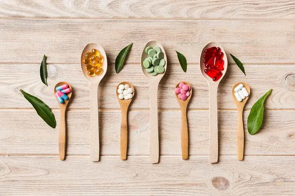 Different dietary supplement pills placed in spoons of varying sizes.