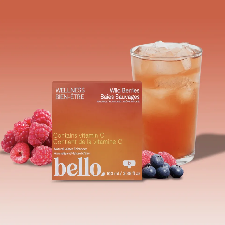 Wild berries vitamin C water enhancer packaging displayed with raspberries and blueberries next to a glass of iced flavored beverage.